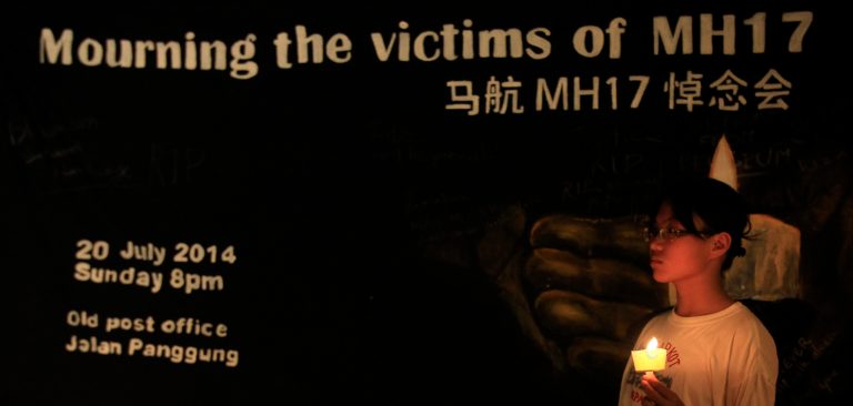 A girl holding a candle stands in front of a banner during an event to mourn the victims of the crashed Malaysia Airlines Flight 17, in Kuala Lumpur, Malaysia, Sunday. (AP/Lai Seng Sin)