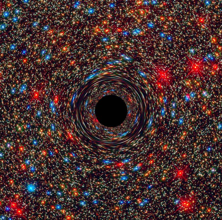 This computer-simulated image shows a supermassive black hole at the core of a galaxy. The black region in the center represents the black holeâs event horizon, where no light can escape the massive objectâs gravitational grip. The black holeâs powerful gravity distorts space around it like a funhouse mirror. Light from background stars is stretched and smeared as the stars skim by the black hole. (NASA)