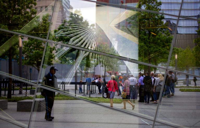 FILE - With an image of the former World Trade Center seen through the reflective windows of the 9/11 Memorial Museum, some of the first public visitors can be seen arriving at the site in New York in this Wednesday, May 21, 2014 file photo. Organizers say over 300,000 people have visited the Sept. 11 museum since it opened little more than a month ago, and that has exceeded their expectations. (AP Photo/Craig Ruttle, File)