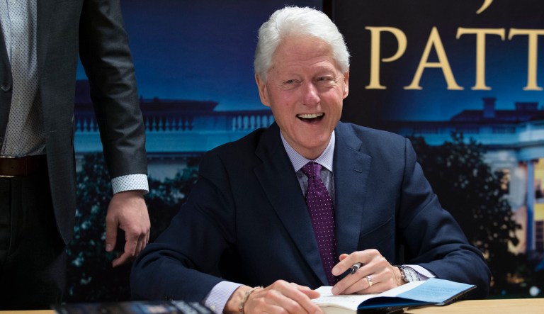 Former President Bill Clinton, left, smiles as he signs autographs during an event to promote his new novel with author James Patterson, "The President is Missing," Tuesday, June 5, 2018, in New York.
