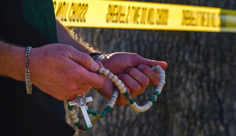 Michael Cole prays the rosary as he joins a group prayer to honor Bishop David O'Connell at the corner of his home in Hacienda Heights, Calif., Sunday, Feb. 19, 2023. According to the Los Angeles County Sheriff's Department, detectives are investigating the death of OâConnell, who was shot and killed Saturday just blocks from a church, as a homicide. 