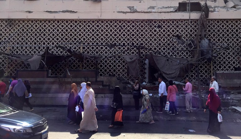 People survey the aftermath of a fiery car crash outside the National Cancer Institute in Cairo, Egypt, Monday, Aug. 5, 2019. The multiple-car crash set off an explosion that ignited a fire at Egypt's main cancer hospital, the government said.