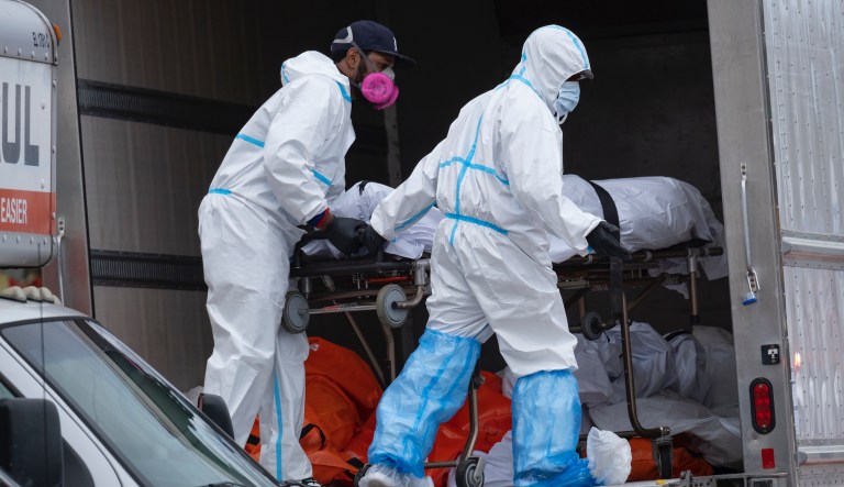 Workers move bodies to a refrigerated truck from the Andrew T. Cleckley Funeral Home in the Brooklyn borough of New York, Wednesday, April 29, 2020. Police responded to a report of human bodies in vehicles, which they determined were connected to the nearby funeral home.