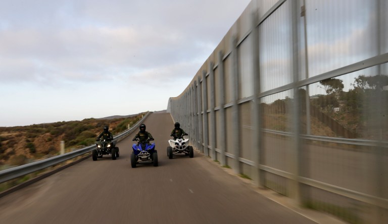 In this Wednesday, June 22, 2016 photo, Border Patrol agents ride all-terrain vehicles along a secondary fence separating Tijuana, Mexico, right, and San Diego in San Diego.