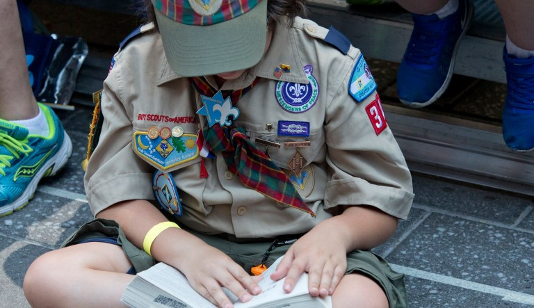 A Boy Scout reads a book during the Second Annual World Championship Pinewood Derby, Saturday, June 25, 2016, in New York's Times Square. Over 250 Boy Scouts ages 7 to 10  from around the United States raced hand-crafted cars on a 45-foot custom race track, achieving speeds up to 40 MPH.