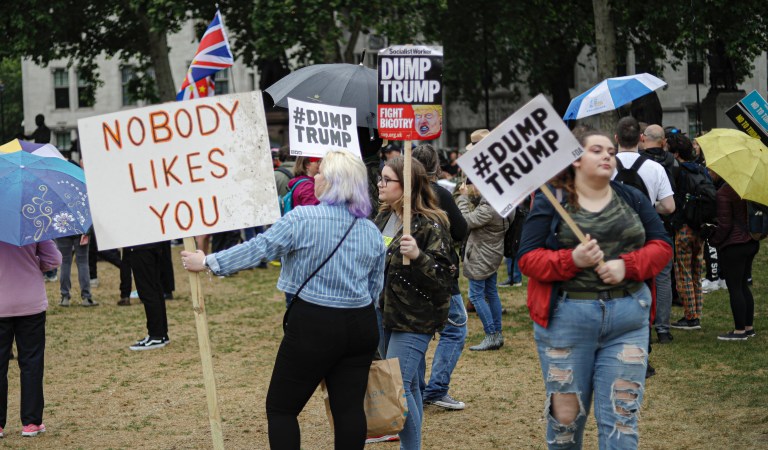 People hold placards with anti-Trump messages in central London, during a protest against the state visit of President Donald Trump.
