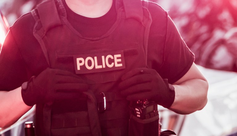 An Hispanic police officer wearing a bulletproof vest.