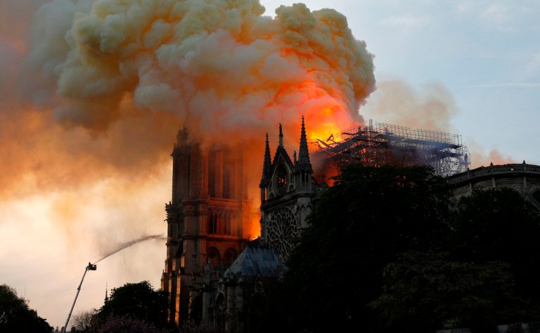 A firefighter uses a hose to douse flames and smoke billowing from the roof at Notre Dame Cathedral in Paris on April 15, 2019.