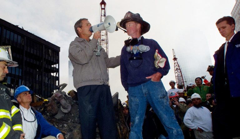 As rescue efforts continue in the rubble of the World Trade Center in New York, President Bush stands with firefighter Bob Beckwith on a burnt fire truck in front of the World Trade Center during a tour of the devastation, Friday, Sept. 14, 2001.