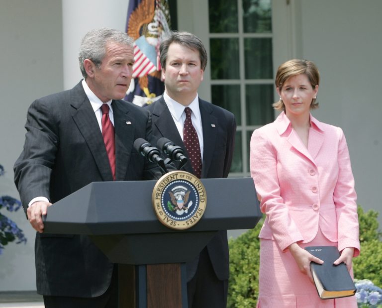 President Bush, speaks in the Rose Garden of the White House before the swearing-in of Brett Kavanaugh, center, as Judge for the U.S. Court of Appeals for the District of Columbia Thursday, June 1, 2006 in Washington. Holding the Bible is Kavanaugh's wife Ashely Kavanaugh.