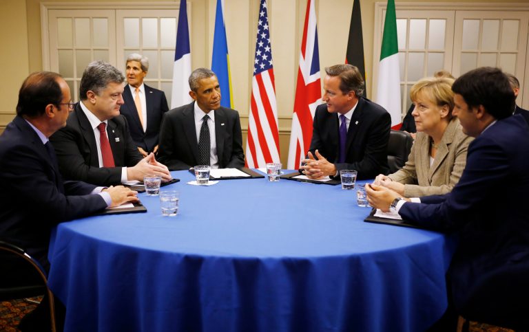 U.S. President Barack Obama, fourth from left, is seated at a table with, from left to right: France's President Francois Hollande; Ukraine President Petro Poroshenko; British Prime Minister David Cameron; German Chancellor Angela Merkel; and Italian Prime Minister Matteo Renzi as they meet about Ukraine at the NATO summit at Celtic Manor in Newport, Wales, Thursday, Sept. 4, 2014. U.S. Secretary of State John Kerry is seated at rear left. (AP Photo/Charles Dharapak)