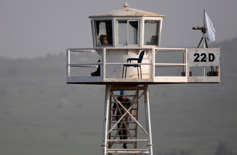 A U.N. peacekeeper from the UNDOF force walks up to a watch tower at the Quneitra Crossing between Syria and the Israeli-controlled Golan Heights, Saturday, March, 9, 2013. (AP Photo/Dan Balilty)