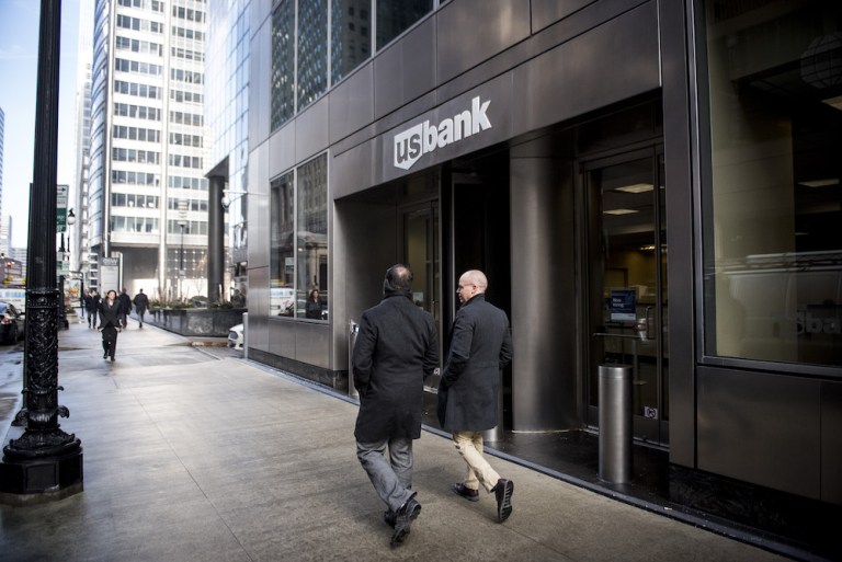Pedestrians pass in front of a U.S. Bank branch in downtown Chicago in January. The lender has agreed to pay $613 million to settle claims that it deliberately scrimped on anti-money laundering safeguards. Photographer: Christopher Dilts/Bloomberg