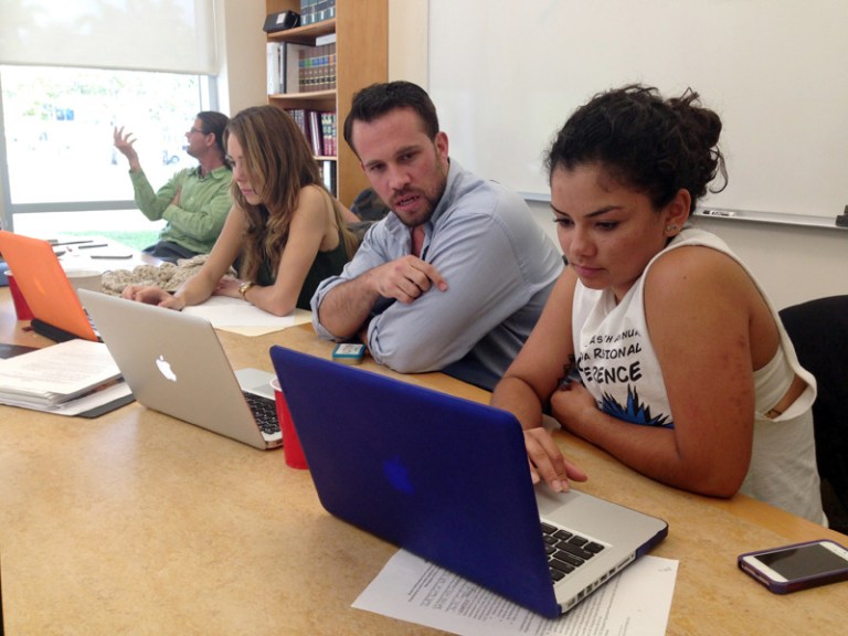 Anthony Rouzier helps Valentina Adarraga, 20, sign up for health insurance under the Affordable Care Act in Miami, Friday, March 21. (AP image)