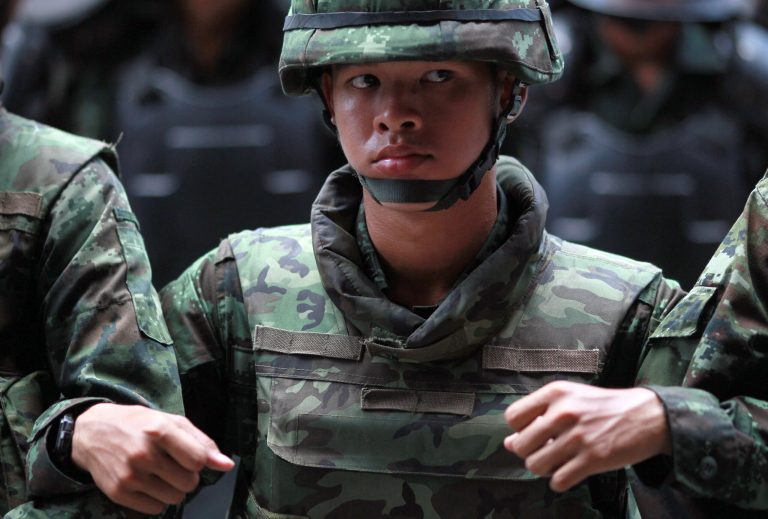 Thai soldiers link arms as they monitor the protest against the coup outside a shopping complex in Bangkok, Thailand Saturday, May 24, 2014. Thailand's coup leaders said Saturday they will keep former Prime Minister Yingluck Shinawatra, Cabinet members and anti-government protest leaders detained for up to a week to give them 