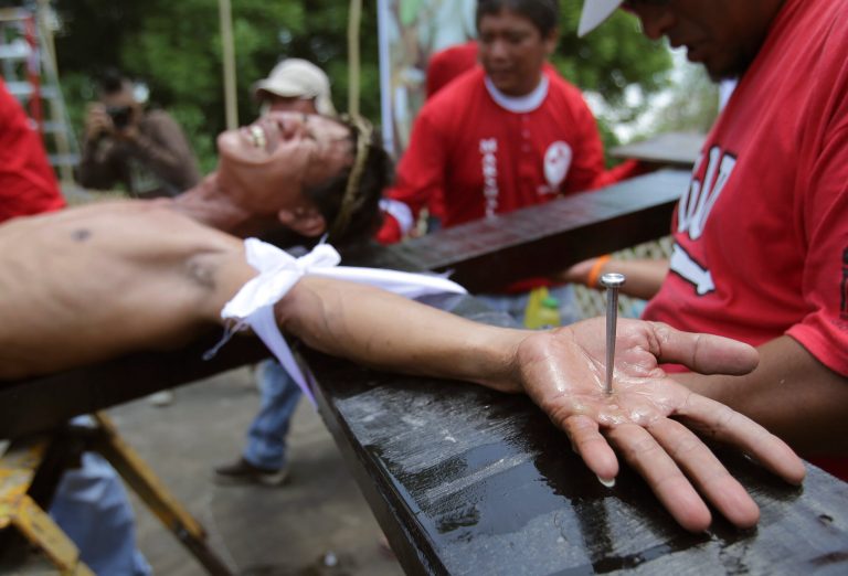 A Filipino devotee grimaces as he is nailed to a cross to re-enact the crucifixion of Jesus Christ in Santa Lucia village, Pampanga province, northern Philippines on Friday, April 18, 2014. Church leaders and health officials have spoken against the practice which mixes Roman Catholic devotion with folk belief, but the annual rites continue to draw participants and huge crowds. (AP Photo/Aaron Favila)