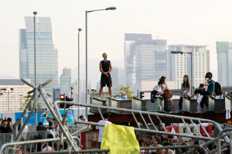 Student protesters stand behind barricades used to occupy the streets surrounding the government headquarters in Hong Kong, China, Sunday, Sept. 28, 2014. Riot police in Hong Kong on Saturday arrested scores of students who stormed the government headquarters compound during a night of scuffles to protest China's refusal to allow genuine democratic reforms in the semiautonomous city. (AP Photo/Wally Santana)