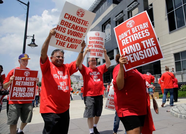 Union members carry protest signs as they march outside the Mercer County Criminal Courthouse before arguments Wednesday, June 25, 2014, in Trenton, N.J., over New Jersey Gov. Chris Christie's plan to use pension payments to balance the budget.  (AP Photo/Mel Evans)