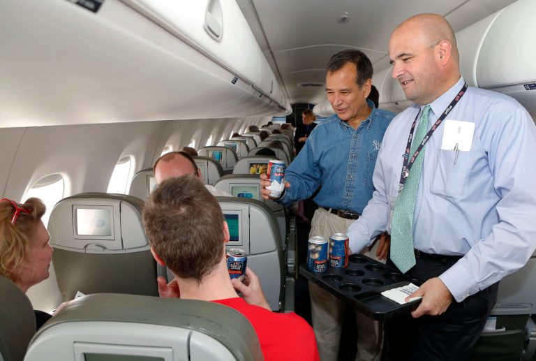 In this Tuesday, July 2, 2013 photo from AP Images for Samuel Adams, Jim Koch, founder and brewer of Samuel Adams, left, and Marty St. George, SVP of Marketing and Commercial at JetBlue hand out Boston Lager cans on the inaugural JetBlue flight from Boston to New York. As the airline industry works to improve its food and beverage options, a new trend has emerged - airlines adding craft beers to their in-flight offerings. Passengers aboard six North American airlines spent more than $11.3 million on beer during a five-month period in 2013, according to GuestLogix, which processes about 90 percent of onboard credit card transactions for North American carriers. (AP Photo/AP Images for Samuel Adams, Bizuayehu Tesfaye)