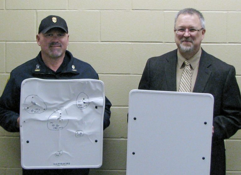 In this April 22, 2013 photo provided by the Cold Spring Record, Cold Spring Police Chief Phil Jones, left, and Rocori School District Superintendent Scott Staska pose with bulletproof white boards in Cold Spring, Minn. Rocori schools are among the first in the nation to acquire the kevlar whiteboards which can be flipped quickly to provide some protection for teachers and students in the event of a shooting. (AP Photo/Cold Spring Record, Mike Austreng)