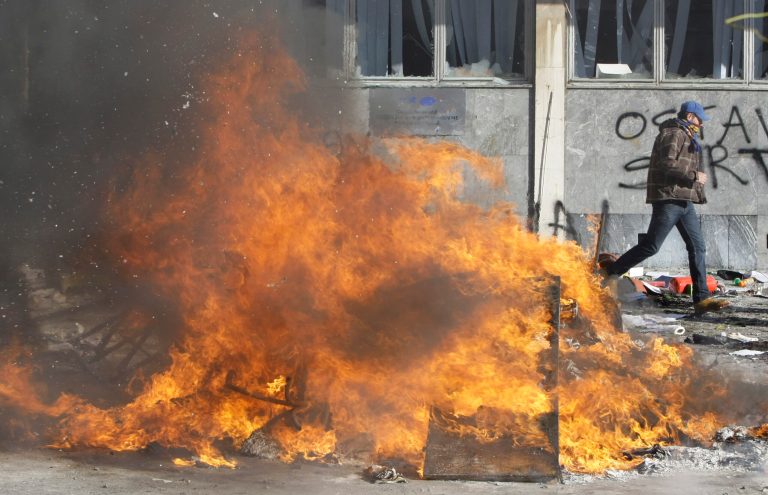 A protester runs from a local government building, during a protest,  in the Bosnian town of Tuzla, Friday, Feb. 7, 2014. Bosnian protesters stormed and set ablaze local government buildings in three Bosnian cities on Friday in fury over unemployment and rampant corruption. At least 90 people were injured. (AP Photo/Amel Emric)