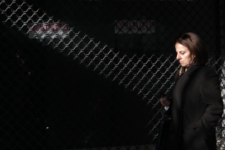   A woman passes a shopping window of a closed shop, with stickers reading 