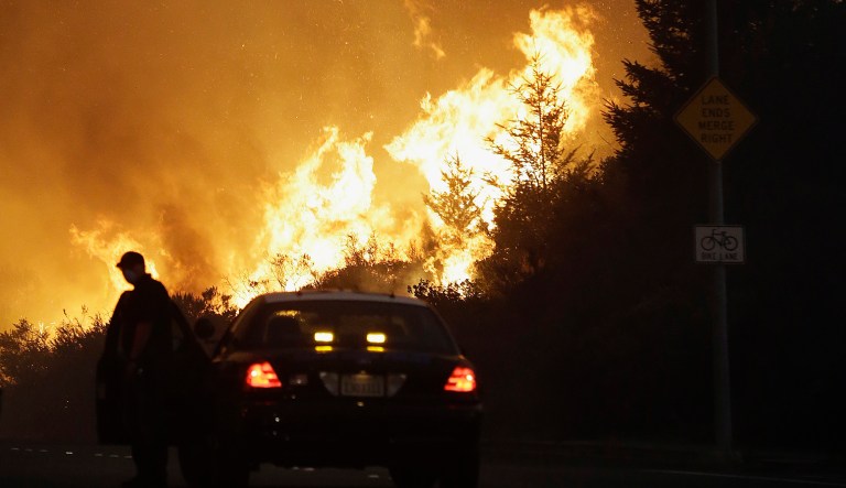 A law enforcement officer blocks a road as flames burn in a residential area in Santa Rosa, Calif., Monday, Oct. 9, 2017. (AP Photo/Jeff Chiu)
