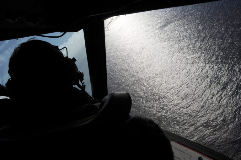 FILE - In this April 13, 2014 file-pool photo, taken from the Royal New Zealand Air Force (RNZAF) P-3K2-Orion aircraft, co-pilot  Squadron Leader Brett McKenzie looks out of a window while searching for debris from missing Malaysia Airlines Flight 370, in the Indian Ocean off the coast of western Australia. The world's two largest commercial aircraft manufacturers are at odds over equipping airliners with black boxes that eject in the event of a crash, making them easier to find. Questions about whether airliners should be equipped with deployable black boxes arose after Malaysia Airlines Flight 370 disappeared in March. The Boeing 777 with 239 people on board still has not been found.  (AP Photo/Greg Wood, File-Pool)