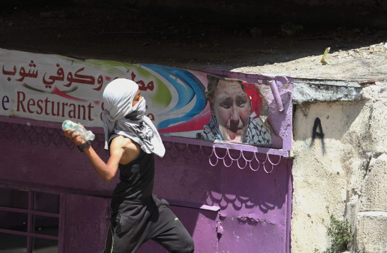 A Palestinian protester throws a glass bottle at Israeli soldiers during clashes, following a protest against the Israeli military action over Hamas in Gaza, in the West Bank city of Hebron on Friday, Aug. 15 , 2014. Israel and Hamas are now observing a five-day temporary cease-fire in an attempt to allow indirect talks in Cairo to continue. The negotiations are meant to secure a substantive end to the monthlong Gaza war and draw up a roadmap for the coastal territory, which has been hard-hit in the fighting. (AP Photo/Nasser Shiyoukhi)