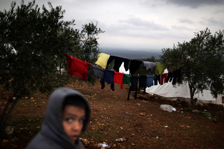  In this Monday, Dec. 10, 2012 photo, a Syrian boy who fled his home with his family walks back to his tent, next to laundry hung on olive trees, at a camp for displaced Syrians, in the village of Atmeh, Syria. This tent camp sheltering some of the hundreds of thousands of Syrians uprooted by the country's brutal civil war has lost the race against winter: the ground under white tents is soaked in mud, rain water seeps into thin mattresses and volunteer doctors routinely run out of medicine for coughing, runny-nosed children. (AP Photo/Muhammed Muheisen)  
