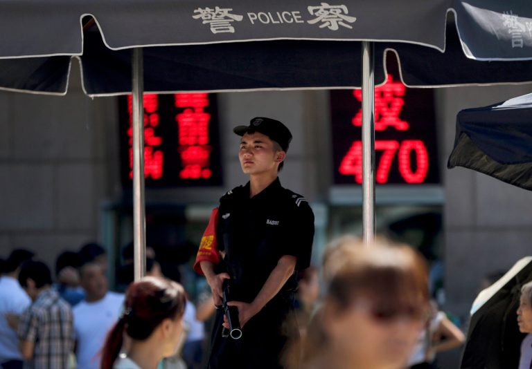 An armed policeman stands guard on a police booth at a crowded railway station in Beijing, China Wednesday, Sept. 3, 2014. Beijing's tight controls and monopoly on the narrative makes it difficult to independently assess if the use of deadly force by police has been justified. Authorities have been on high alert to prevent more attacks by Uighur militants who over the few years have killed dozens of civilians in train stations and other public places. Already in some cities, patrolling SWAT units have been authorized to shoot dead suspected terrorists without warning. (AP Photo/Andy Wong)