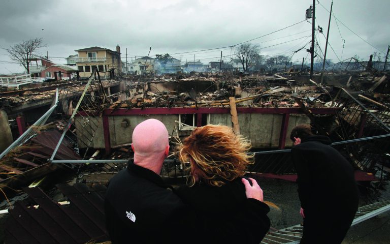 FILE - In this Tuesday, Oct. 30, 2012 file photo, Robert Connolly, left, embraces his wife, Laura, as their son Kyle leans over, at right, as they survey the remains of the home owned by Laura's parents that burned to the ground in the Breezy Point section of New York, following Superstorm Sandy. Sandy ran up a $42 billion bill on New York and the state and New York City are making big requests for disaster aid from the federal government, according to one of Gov. Andrew Cuomo's administration officials. (AP Photo/Mark Lennihan, File)
