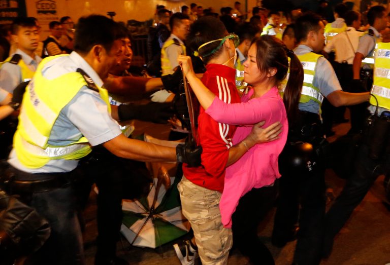 Police officers push the protesters out to a nearby park to clear the main roads outside government headquarters in Hong Kong's Admiralty, Wednesday, Oct. 15, 2014. Hundreds of Hong Kong police officers moved in early Wednesday to clear pro-democracy protesters out of a tunnel outside the city government headquarters in the latest escalation of tensions in a weeks long political crisis. Officers, many of them in riot gear and wielding pepper spray, tore down barricades and concrete slabs around the underpass. (AP Photo/Kin Cheung)