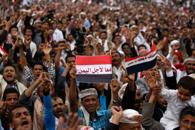 A Yemeni government supporter holds a representation of the national flag with Arabic writing that reads, 