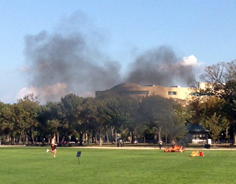 In this photo provided by Katy Scheflen, people run to a man who set himself on fire on the National Mall in Washington, Friday, Oct. 4, 2013. The reason for the self-immolation was not immediately clear and the man's identity was not disclosed. (AP Photo/Katy Scheflen)