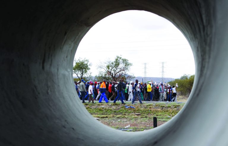 Striking platinum miners take part in a march to the Rustenburg, South Africa, police station, Sunday, Sept. 16, 2012 to protest the heavy handed way the police are cracking down on strikers who have been off work since early last month. The march was declared illegal by the police, who prevented the protesters from entering the town, and the strikers dispersed peacefully. (AP Photo/Denis Farrell)