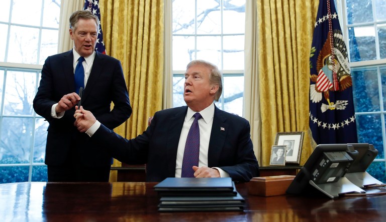 President Trump, hands the pen he used to sign Section 201 actions to U.S. Trade Representative Robert Lighthizer, during a ceremony in the Oval Office of the White House in Washington, Tuesday, Jan. 23, 2018. Trump says he is imposing new tariffs to 