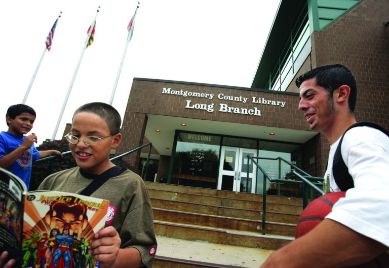 21mdLIBRARYChristopher Amaya, 11 reads a comic book while neighborhood friends Juan Andino 17, right,  and Alfredo Diez, 12, left,  all of Silver Spring, hang out in front of the Long Branch Library in Silver Spring on Thursday, September 20, 2007. Andino, who was aware of increased law enforcement at the library said that he fells safe, and that even though incidents happen, that they are on rare occasion.  He characterized the incidents as fighting and cliques between kids about 15 years old. He was heading to the library to play chess.   Greg Whitesell/Examiner