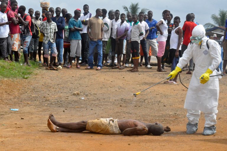 A health worker, right, sprays a man with disinfectant chemicals as he is suspected of dying due to the Ebola virus as people, rear, look on in Monrovia, Liberia, Thursday, Sept. 4, 2014. As West Africa struggles to contain the biggest ever outbreak of Ebola, some experts say an unusual but simple treatment might help: the blood of survivors. The evidence is mixed for using infection-fighting antibodies from survivors' blood for Ebola, but without any licensed drugs or vaccines for the deadly disease, some say it's worth a shot. (AP Photo/Abbas Dulleh)