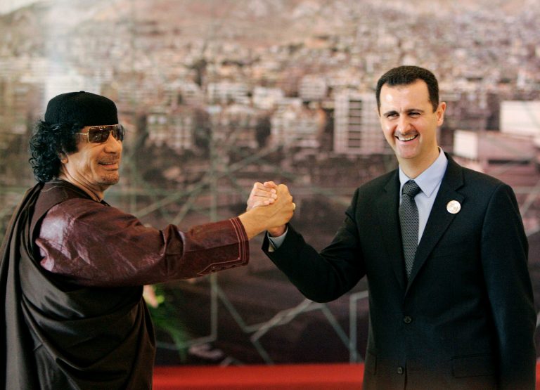 Libyan leader Moammar Gadhafi, left, clasps hands with Syrian President Bashar Assad, right. (AP Photo/Hussein Malla, File)