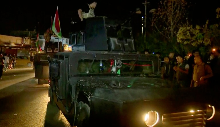 This image made from a video provided by RUDAW TV shows what the Irbil-based Kurdish broadcaster says are Peshmerga fighters and volunteers arriving on military trucks in Kirkuk, Iraq, Monday, Oct. 16, 2017. (RUDAW TV via AP)