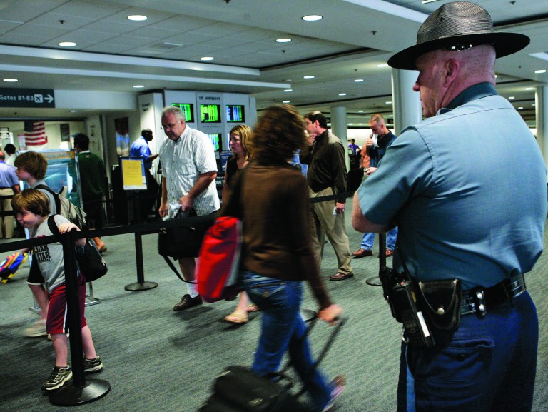 FILE - In this Thursday, Aug. 10, 2006 file photo, a Massachusetts state trooper keeps watch over travelers making their way through Logan International Airport in Boston. Transportation Security Administration officers at Boston's Logan International Airport are alleging that a program intended to help flag possible terrorists based on passengers' mannerisms has led to rampant racial profiling, the New York Times reported Saturday, Aug. 11,2012.(AP Photo/Elise Amendola, File)