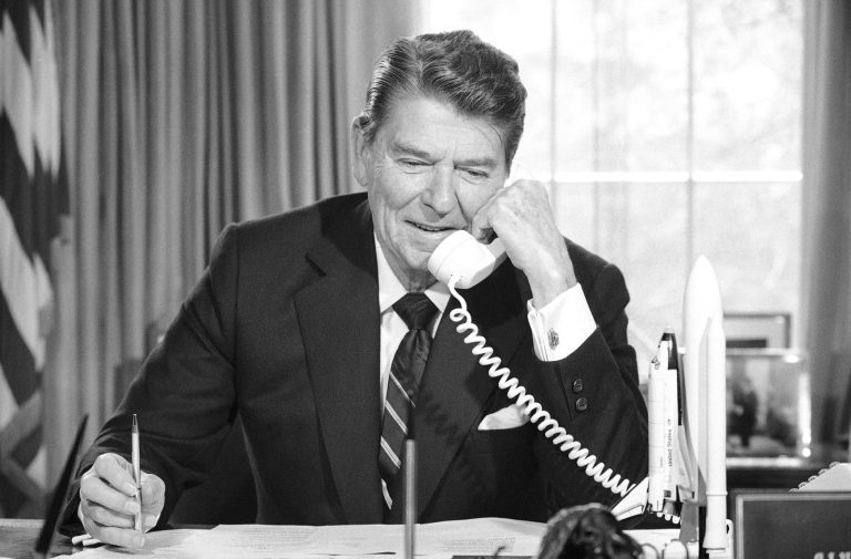 Former President Ronald Reagan speaks by radio-phone from the Oval Office of the White House in Washington in April 1984. (AP Photo/Barry Thumma)