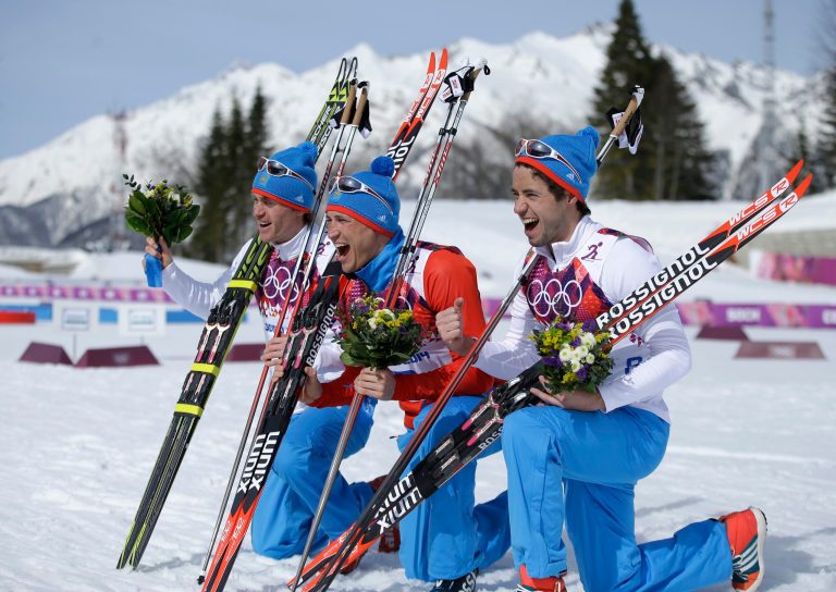 Russia's gold medal winner Alexander Legkov is flanked by Russia's silver medal winner Maxim Vylegzhanin, left and Russia's bronze medal winner Ilia Chernousov during the flower ceremony of the men's 50K cross-country race at the 2014 Winter Olympics, Sunday, Feb. 23, 2014, in Krasnaya Polyana, Russia. (AP Photo/Gregorio Borgia)