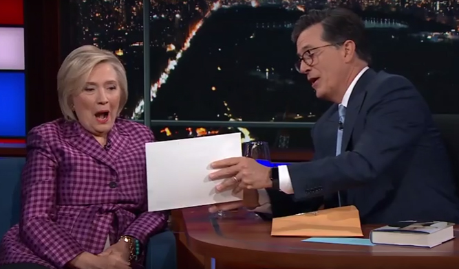Stephen Colbert gave the packet to Clinton, joking that she should 