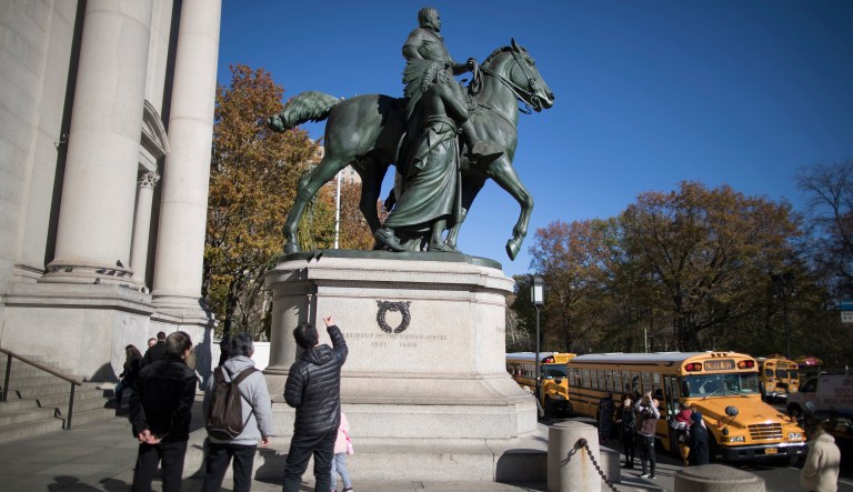 Visitors to the American Museum of Natural History look at a statue of Theodore Roosevelt, which includes a man in a Native American headdress, Friday, Nov. 17, 2017, in New York. (AP Photo/Mary Altaffer)