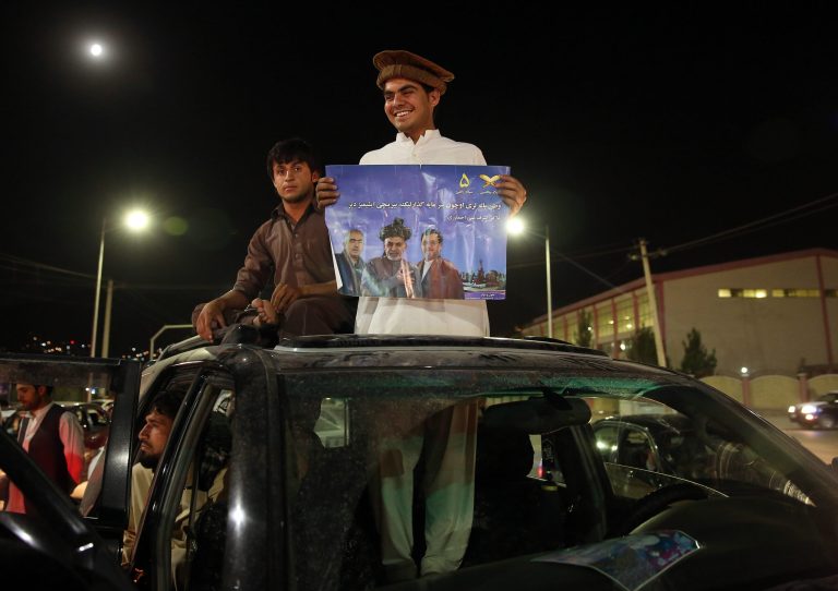 A supporter of Afghanistan's presidential candidate Ashraf Ghani Ahmadzai, holds his poster as he and scores of others celebrate in Kabul, Afghanistan, Monday, July 7, 2014.  Afghan officials released preliminary election results Monday showing former finance minister Ashraf Ghani Ahmadzai well in the lead for the presidency but said no winner can be declared because millions of ballots were being audited for fraud. The announcement came as Ahmadzai is locked in a standoff with his rival Abdullah Abdullah, who has refused to accept any results until all fraudulent ballots are invalidated. (AP Photo/Massoud Hossaini)