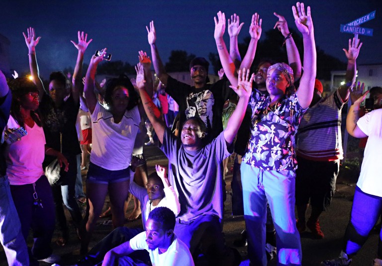 In this Aug. 9, 2014, file photo, a crowd gathers near the scene where 18-year-old Michael Brown was fatally shot by police in Ferguson, Mo. (AP Photo/St. Louis Post-Dispatch, David Carson, File)