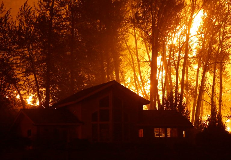 A wildfire burns behind a home on Twisp River Road, Thursday, Aug. 20, 2015 in Twisp, Wash. (AP Photo/Ted S. Warren)