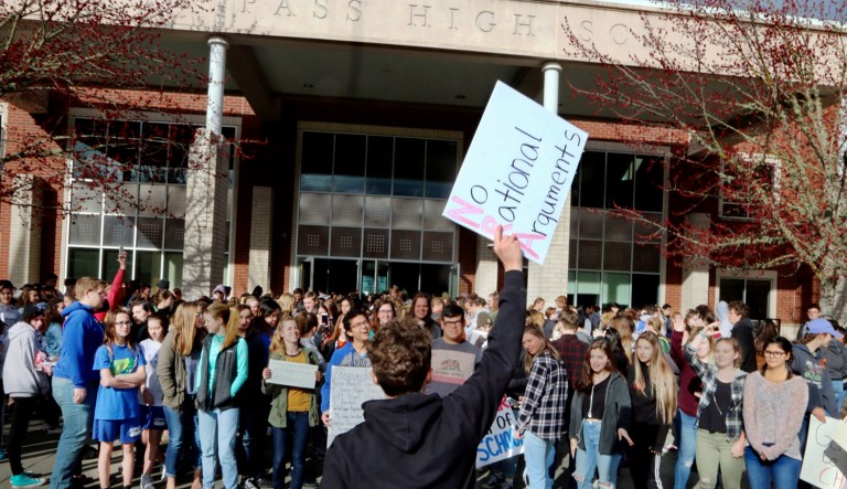 FILE - In this Wednesday, March 14, 2018, file photo, Grants Pass High School senior Zeke Medley, center, leads classmates during a walkout by several hundred students in Grants Pass, Ore. Religious leaders in Oregon intend to harness the youthful campaign for gun control to gather enough signatures to put a ban on assault rifles on the statewide ballot in November.